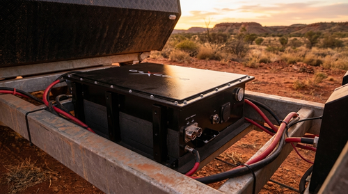 OzX DCX battery mounted under a caravan at a remote outback free camp site at dusk