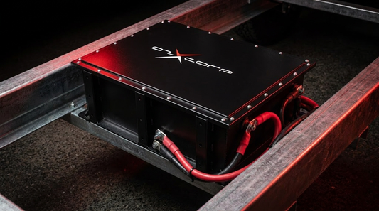 Close-up of an OzX DCX chassis-mount battery bolted between caravan steel frame rails